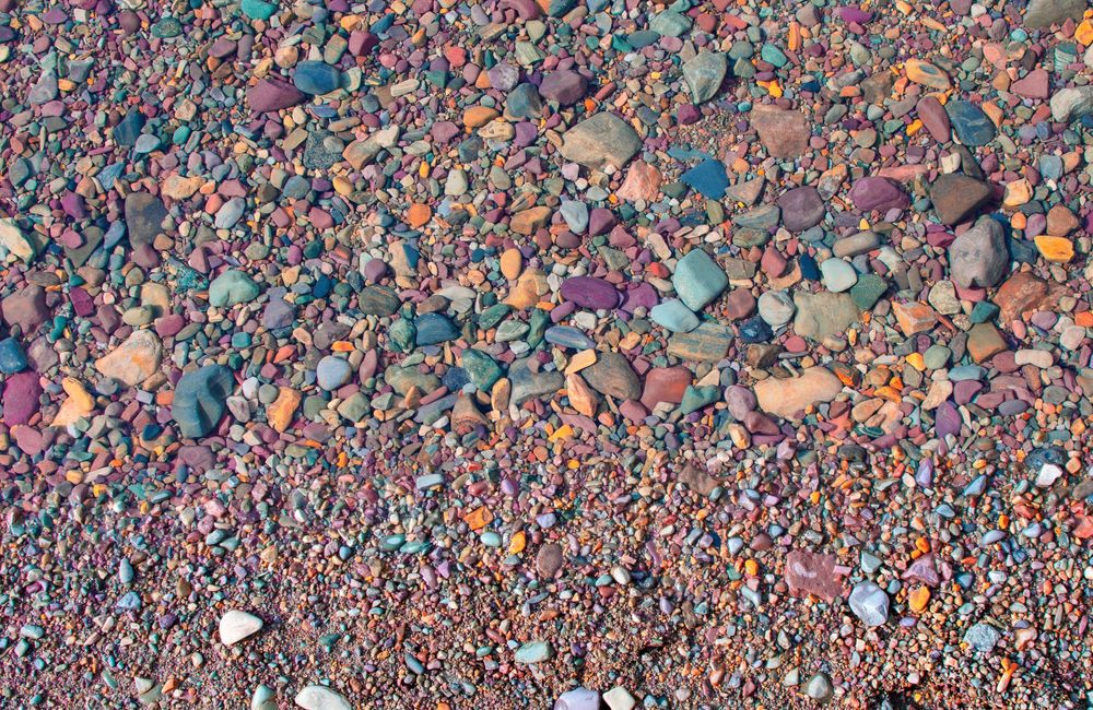 Colorful assortment of smooth multicolored pebbles and rocks on a beach shoreline.