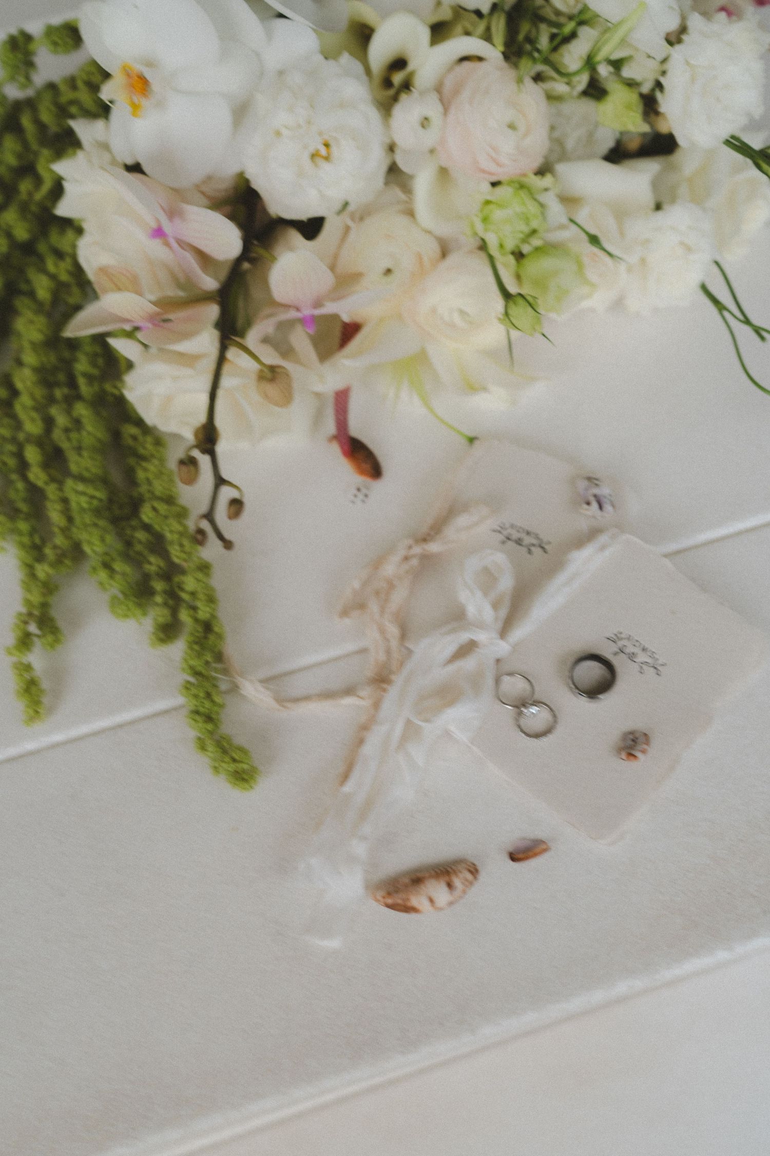 photos with shells and flowers of vow books and rings for eloping couple
