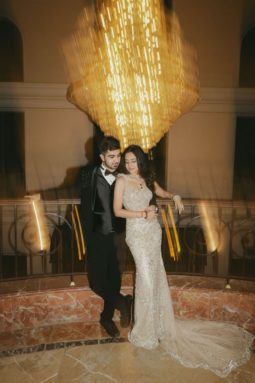 Bride and groom share first dance under golden chandelier in elegant venue.