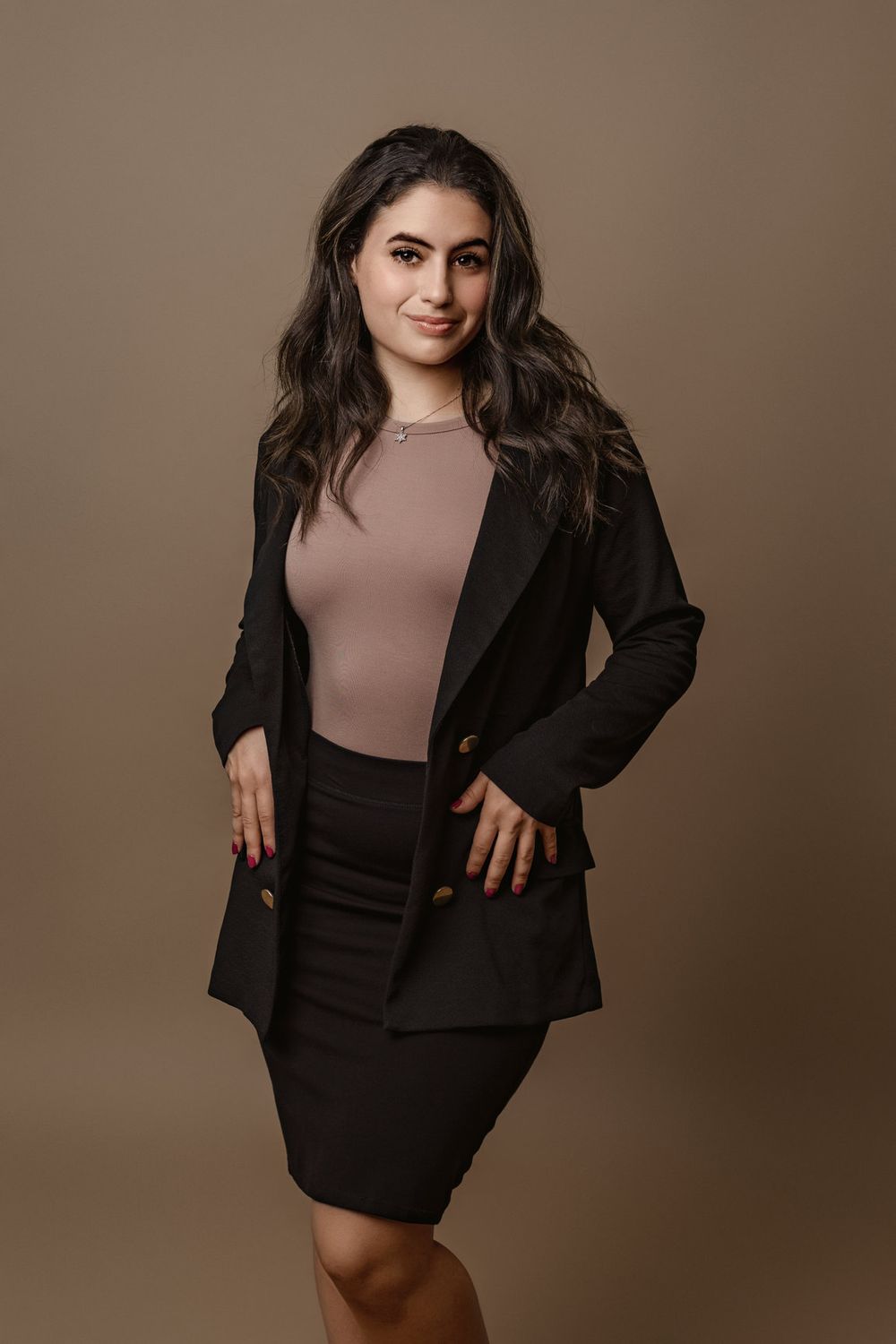Miami mini headshot portrait of a woman in a black blazer against a warm neutral studio background.
