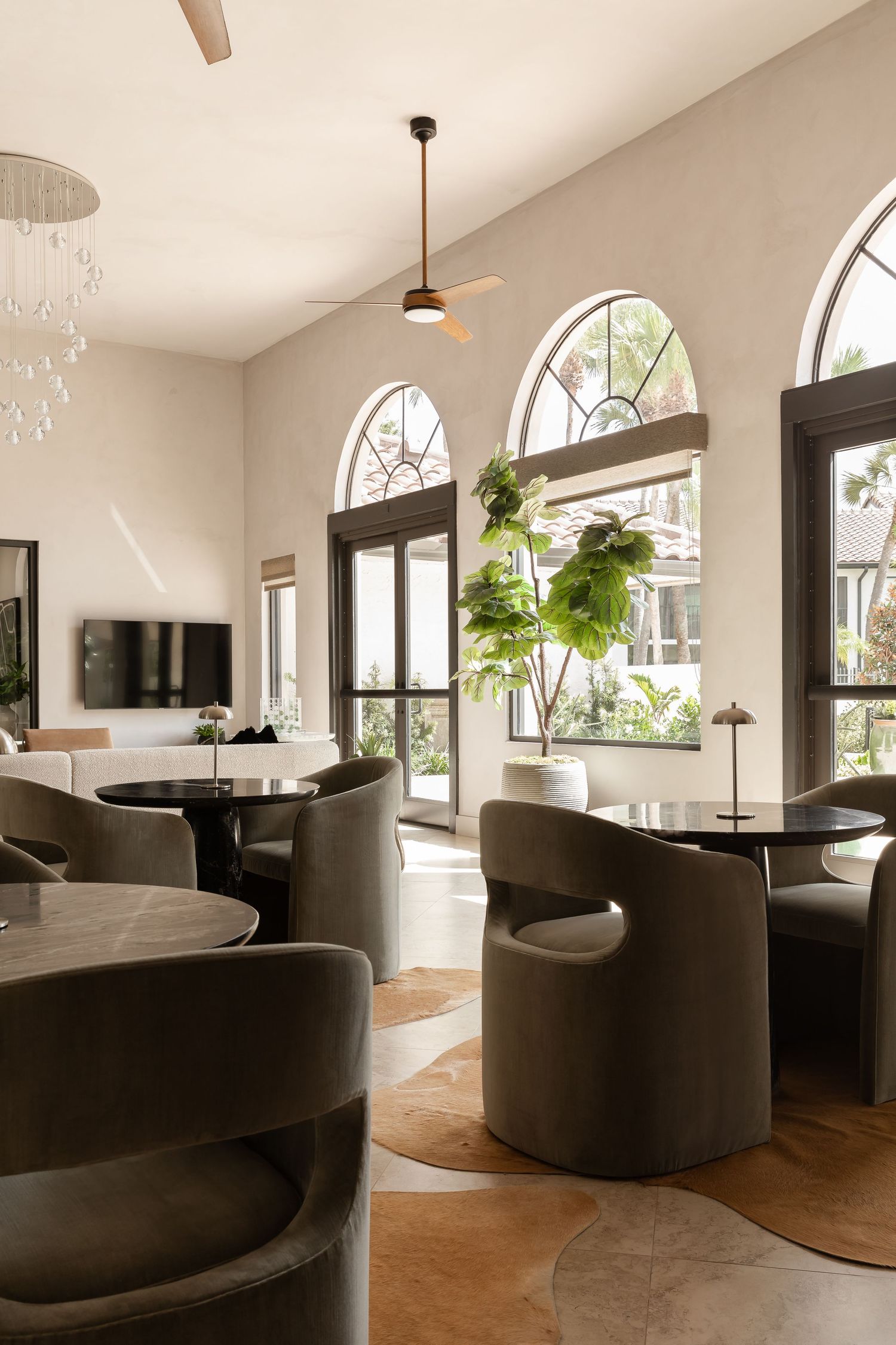 Modern luxury living room with white curved sofa, marble coffee table, and lush indoor plants.