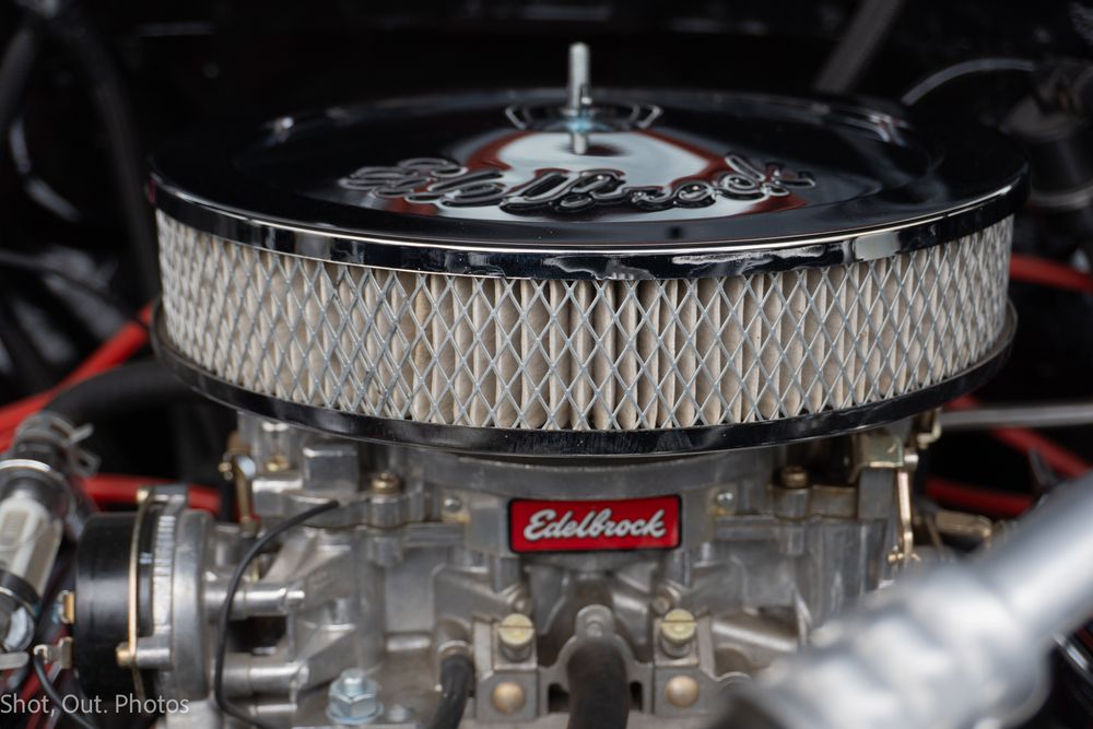 Close-up of a chrome Edelbrock carburetor and air filter on a classic car engine.