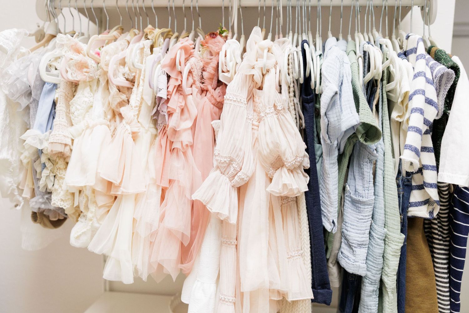 Colorful children's dresses and clothes hanging on a retail clothing rack in a boutique store.