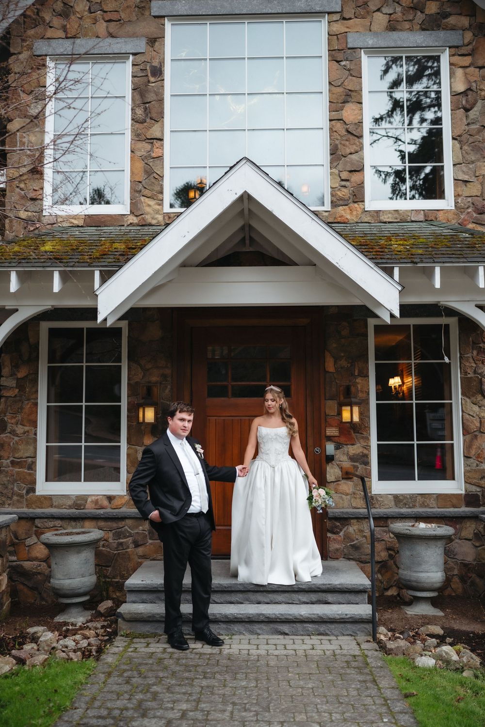 Bride and groom pose together on stone steps of rustic venue entrance on their wedding day.