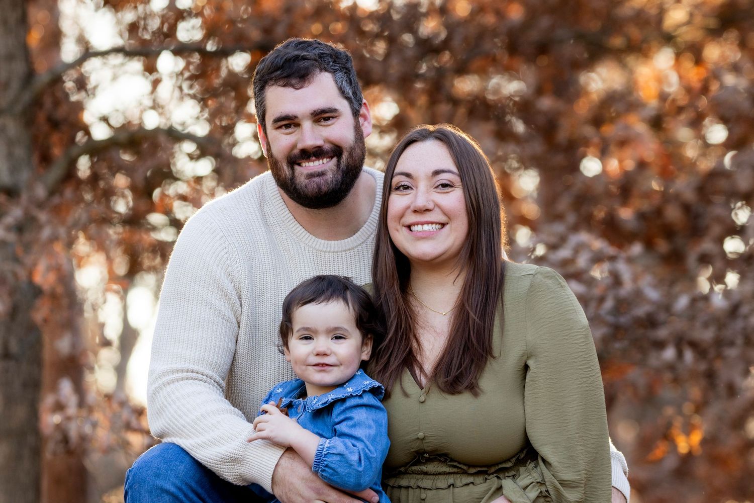 Happy family of four sitting on outdoor steps, parents with two young children, smiling in a garden setting.
