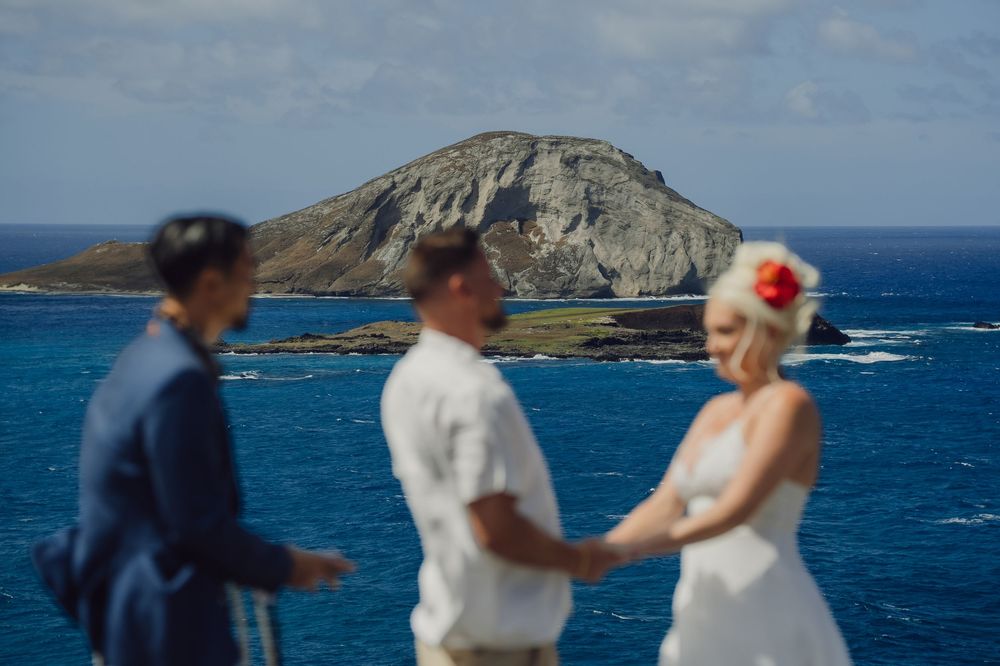 Couple exchanges vows at a stunning Hawaii coastal wedding with turquoise ocean and volcanic island backdrop.
