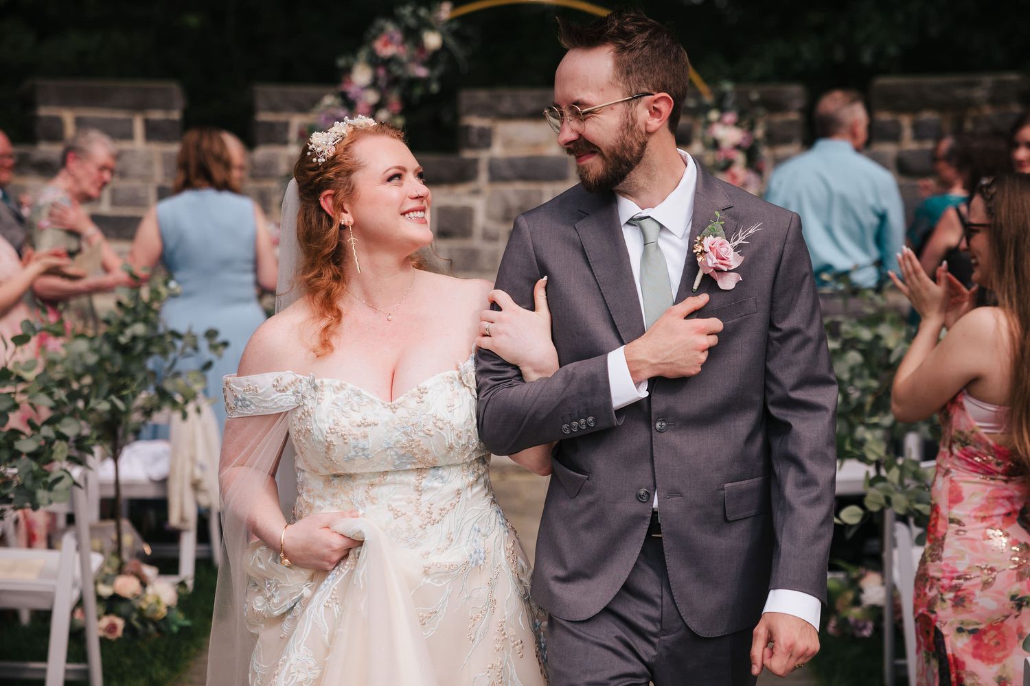 Bride and groom walking arm in arm down the aisle after the ceremony, guests turning to watch.