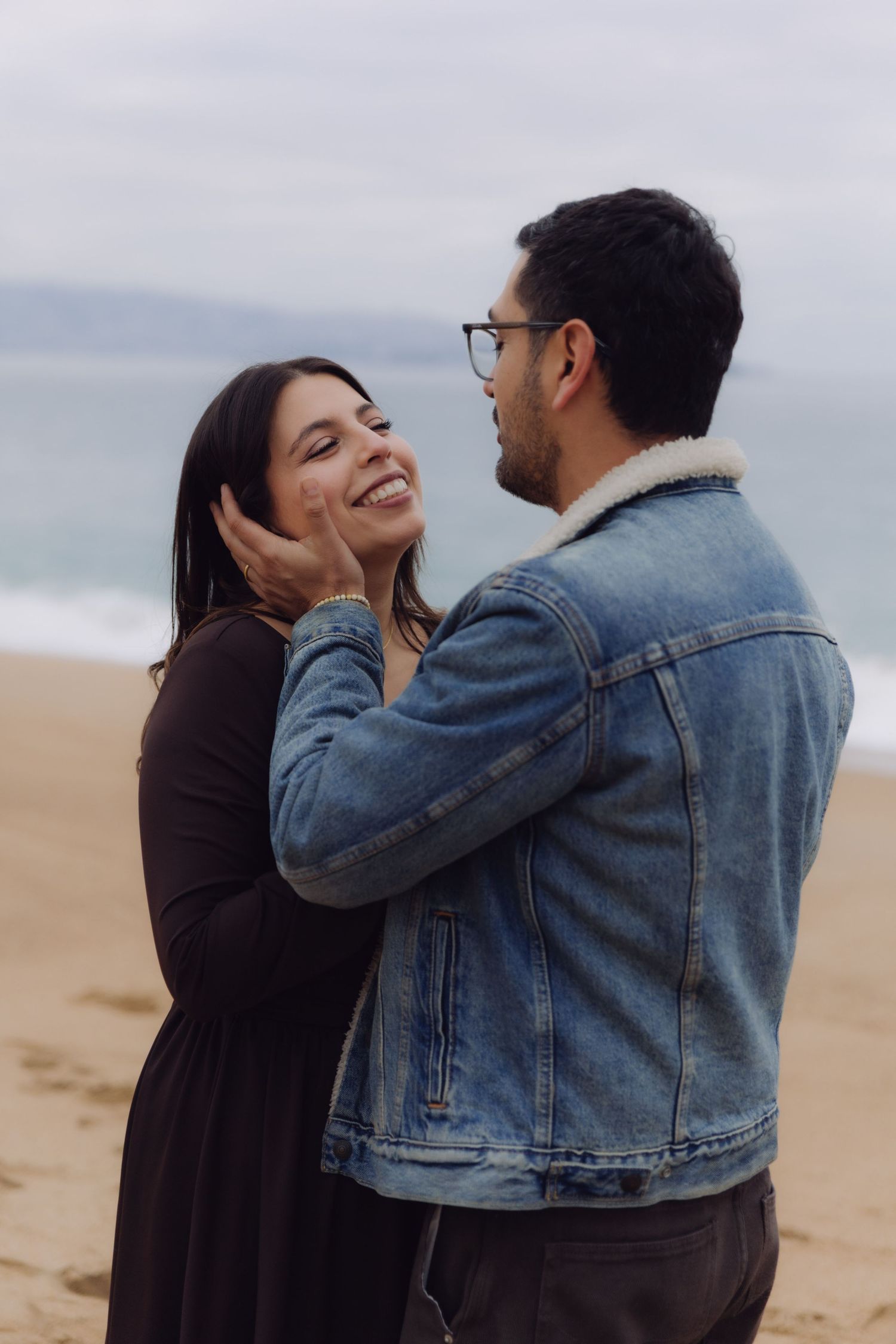 Couple sharing a romantic moment on the beach, man tenderly holding womans face.