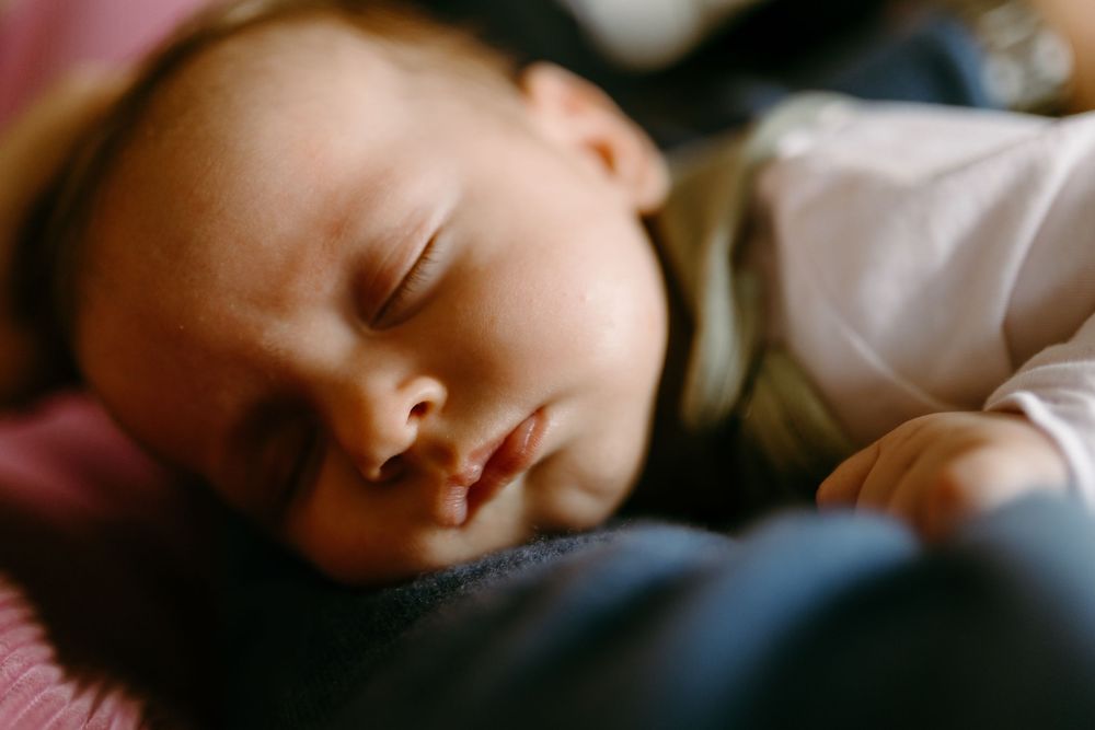 Peaceful newborn baby sleeping soundly, close-up portrait of infant with soft skin and delicate features.