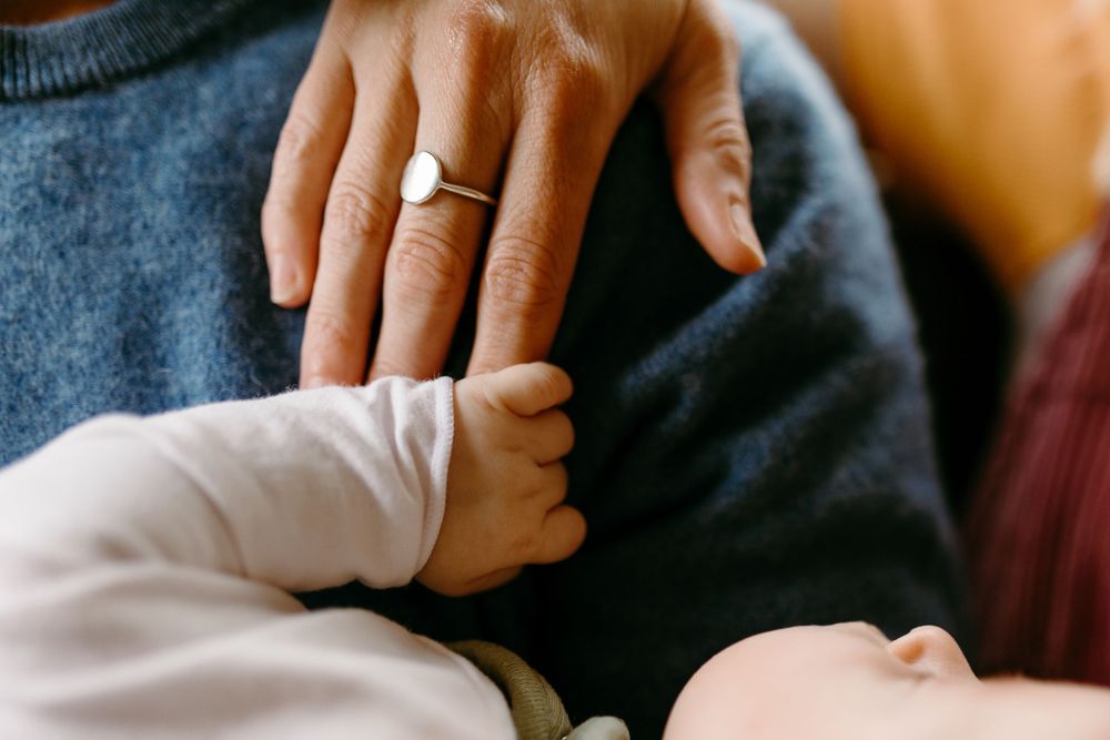 Close-up of adult hands and a newborn baby gently holding fingers, symbolizing family love and new parenthood.