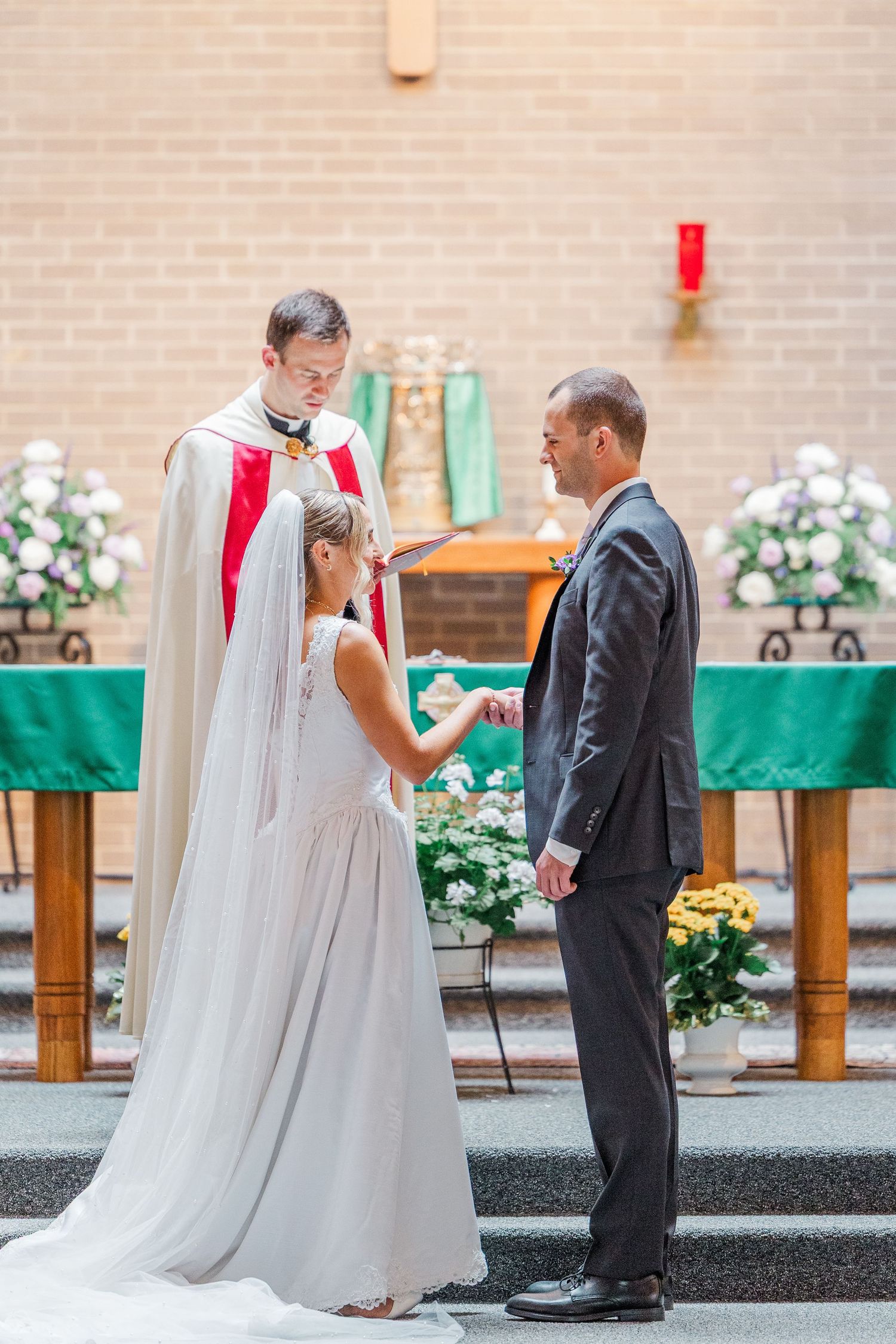 Bride and groom exchange vows before a priest at a church altar during a traditional wedding ceremony.