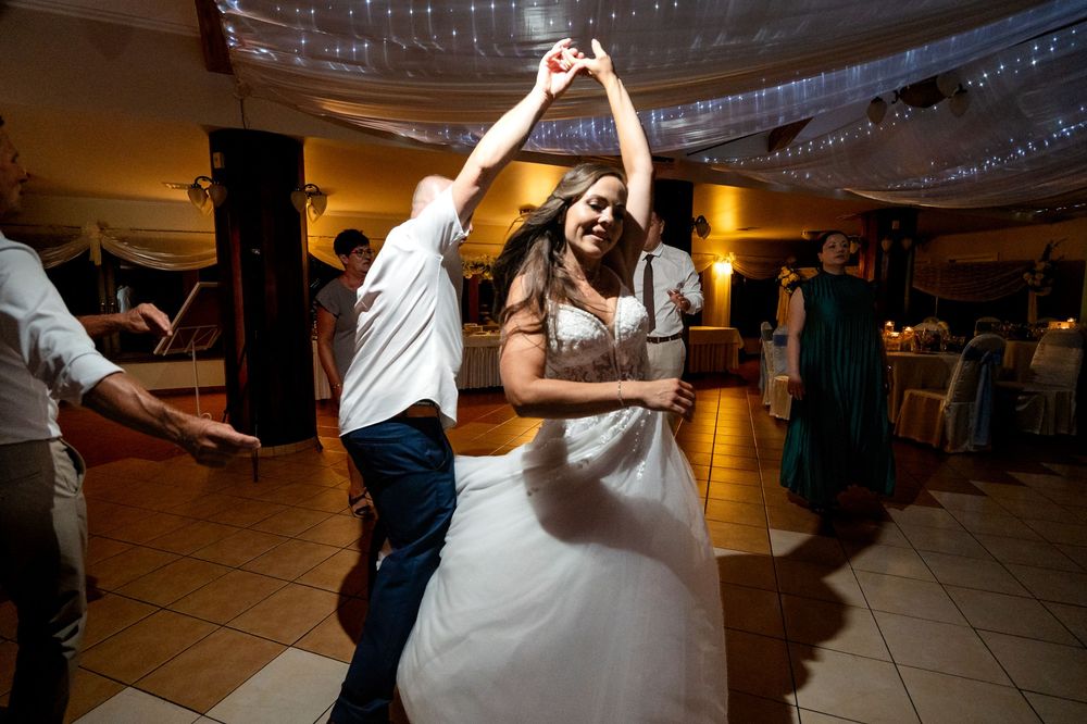 Bride and groom sharing a joyful first dance at their wedding reception in a warmly lit ballroom.