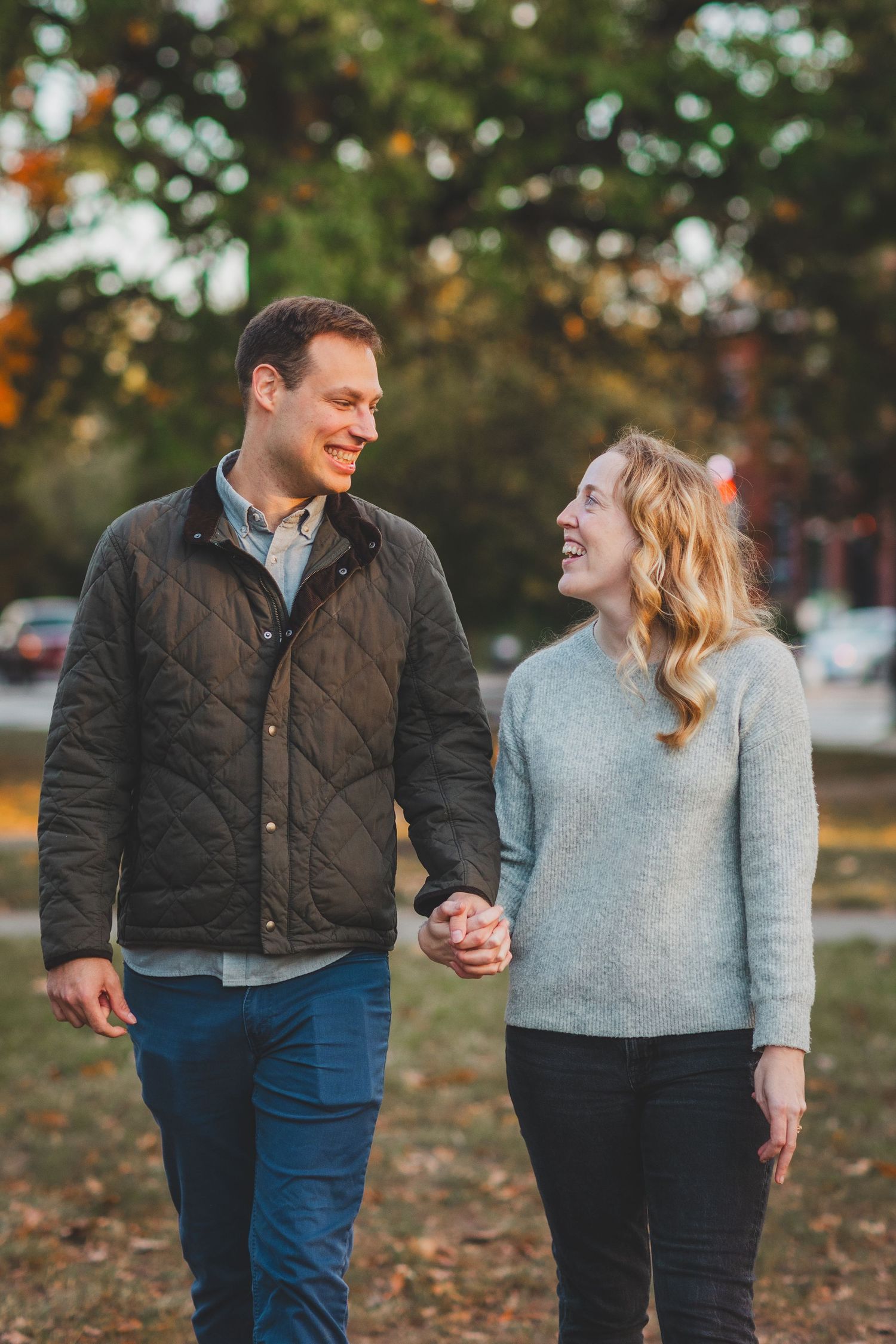 Newly engaged couple smiling warmly on a Capitol Hill sidewalk surrounded by vibrant autumn foliage in Washington DC