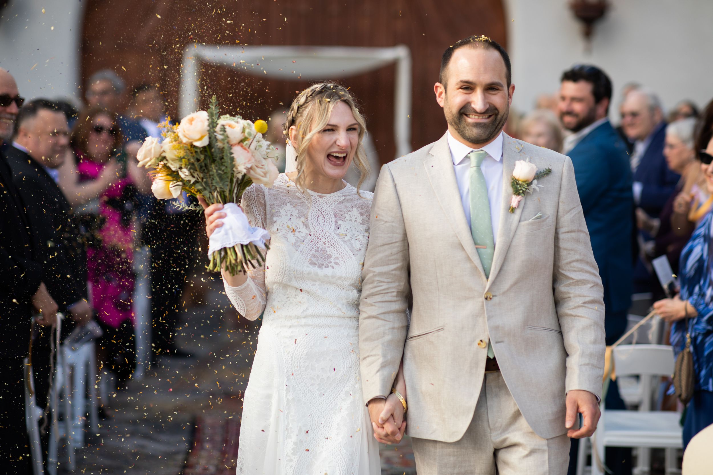 Joyful newlyweds walk down the aisle as guests toss rice at their outdoor wedding ceremony.