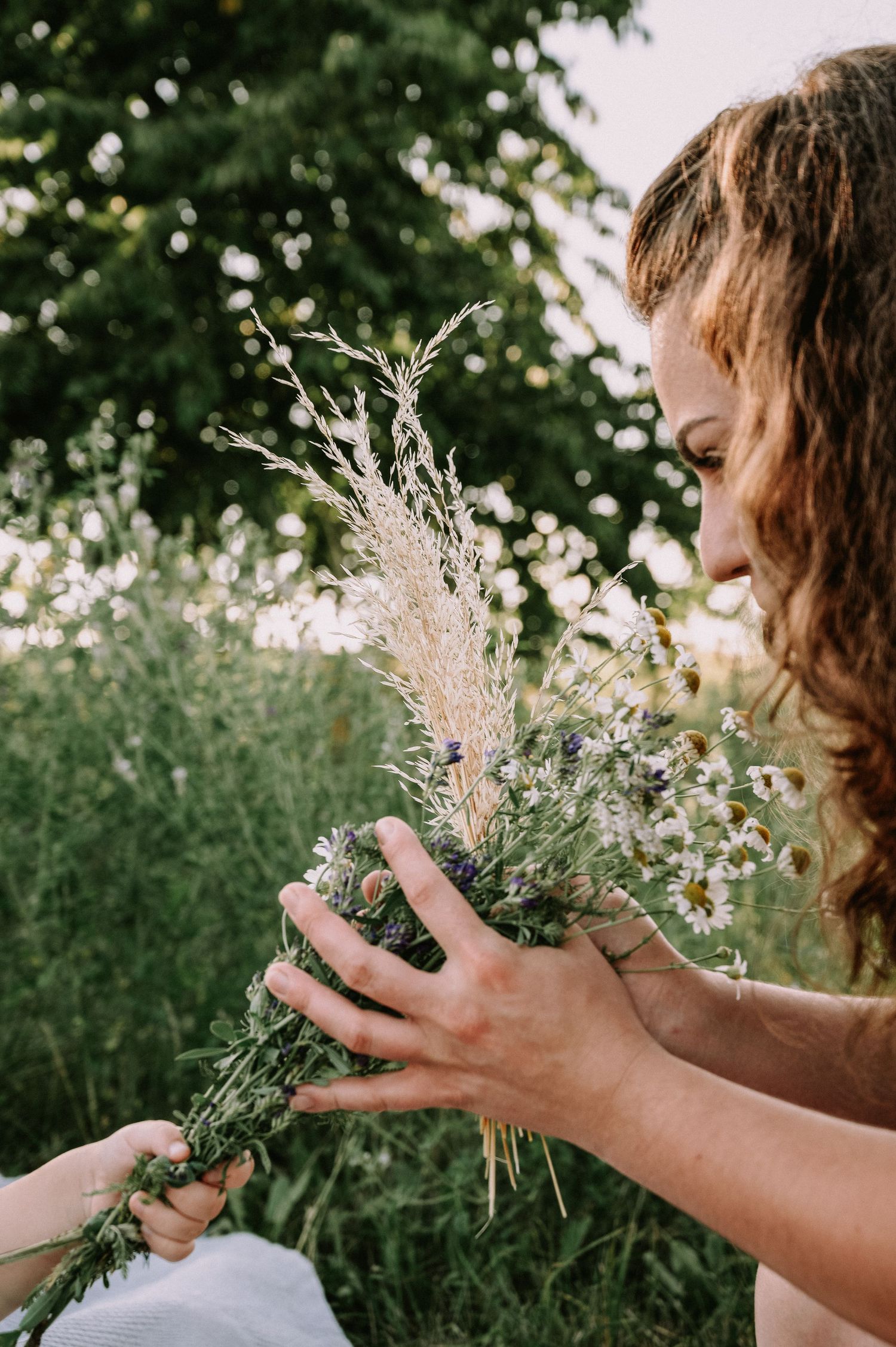 Frau hält einen natürlichen Blumenstrauß auf einer sommerlichen Wiese.