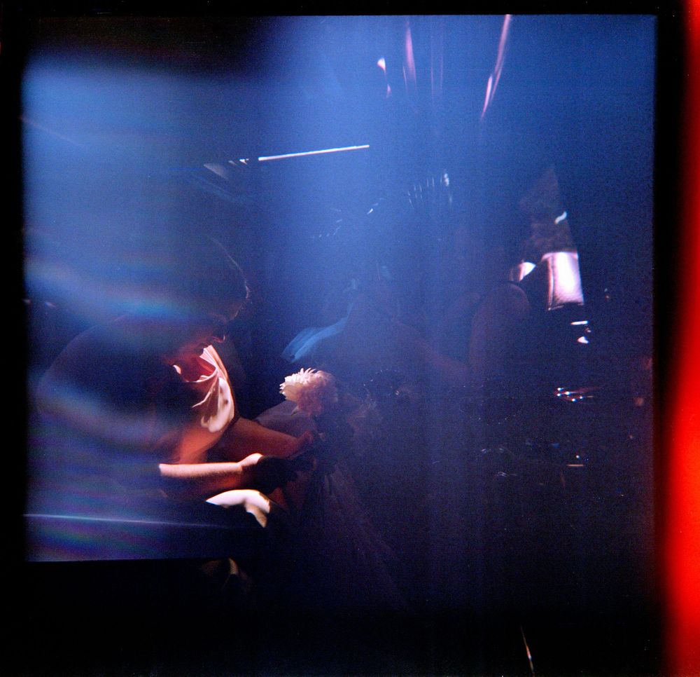 Abstract blurred image of dancers performing under dramatic blue and red stage lighting.