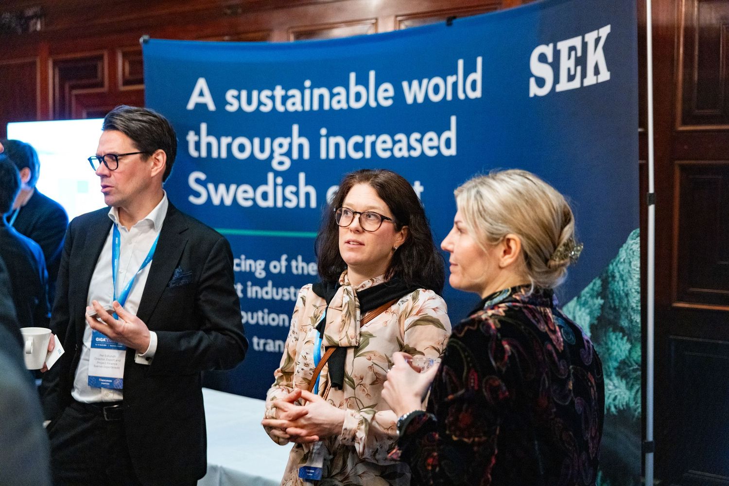 Three professionals conversing near a roll-up.