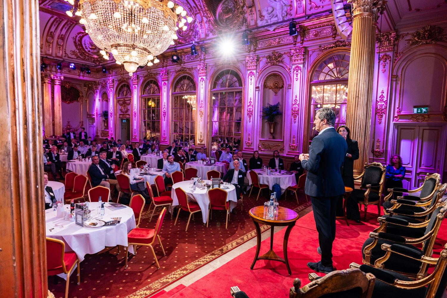 Attendees seated beneath ornate chandeliers and pink lighting at Grand Hotels Spegelsalen