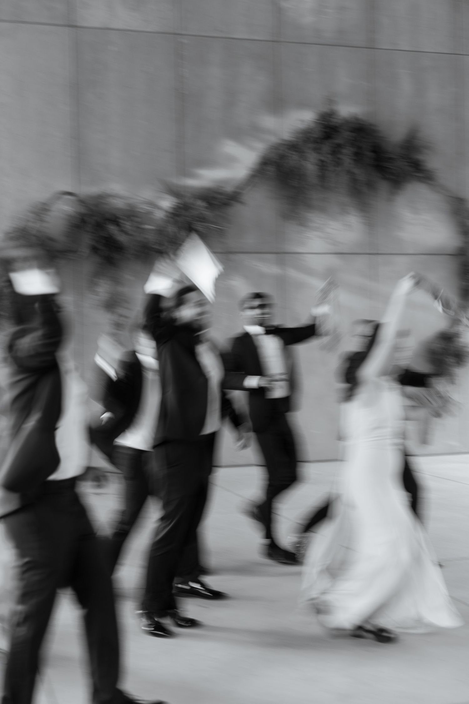 Black and white motion blur photo of a wedding party celebrating with the bride in a white gown.