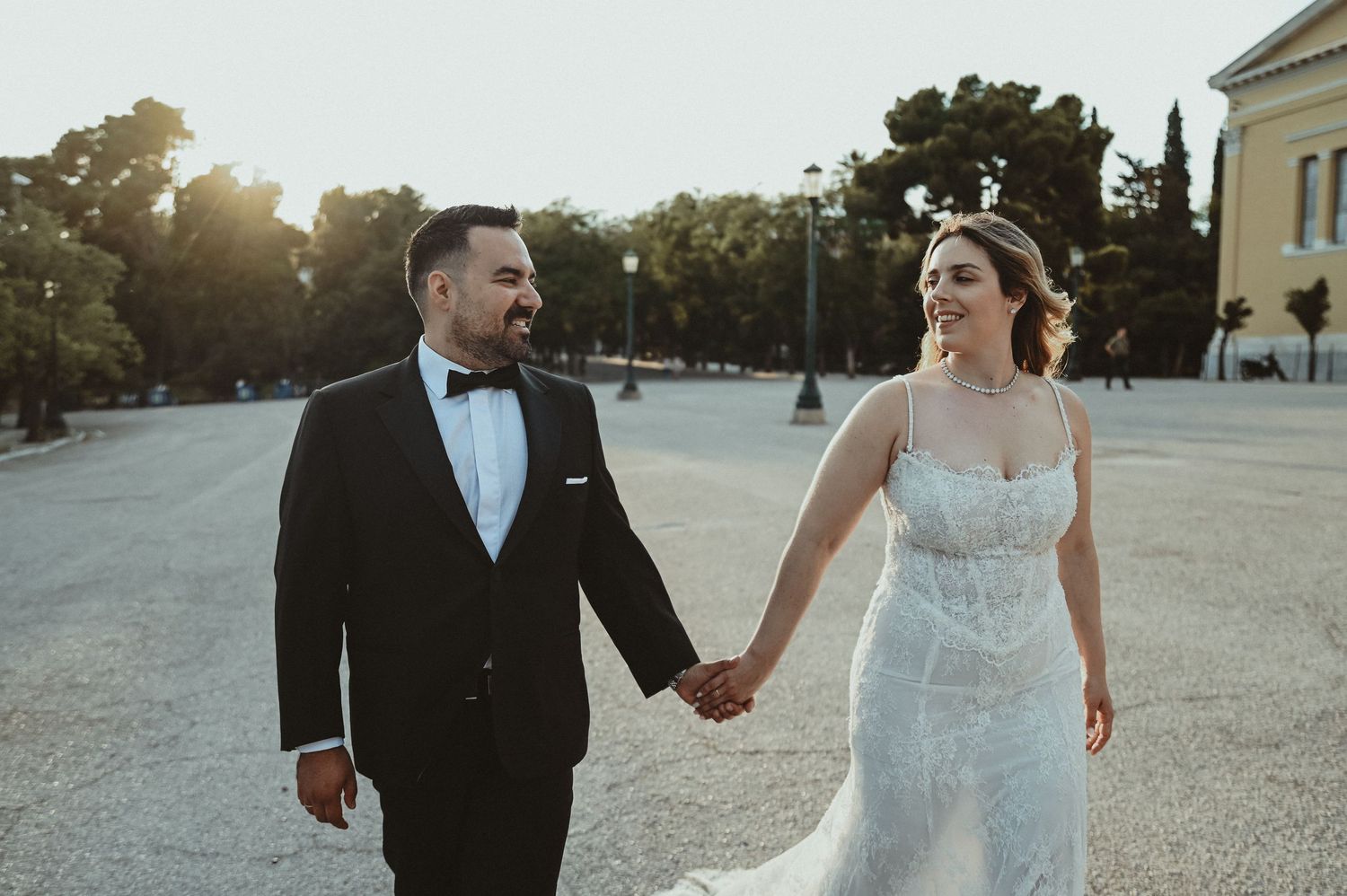Black and white wedding photo of bride and groom gazing at each other outdoors among trees.