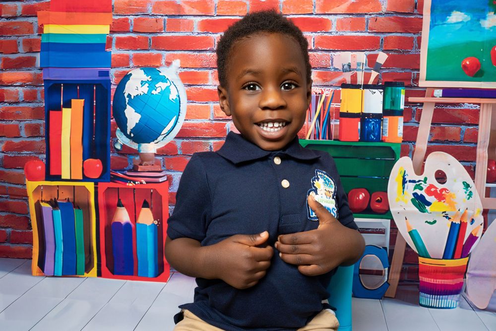 Smiling young boy in navy school uniform poses confidently against vibrant classroom backdrop.