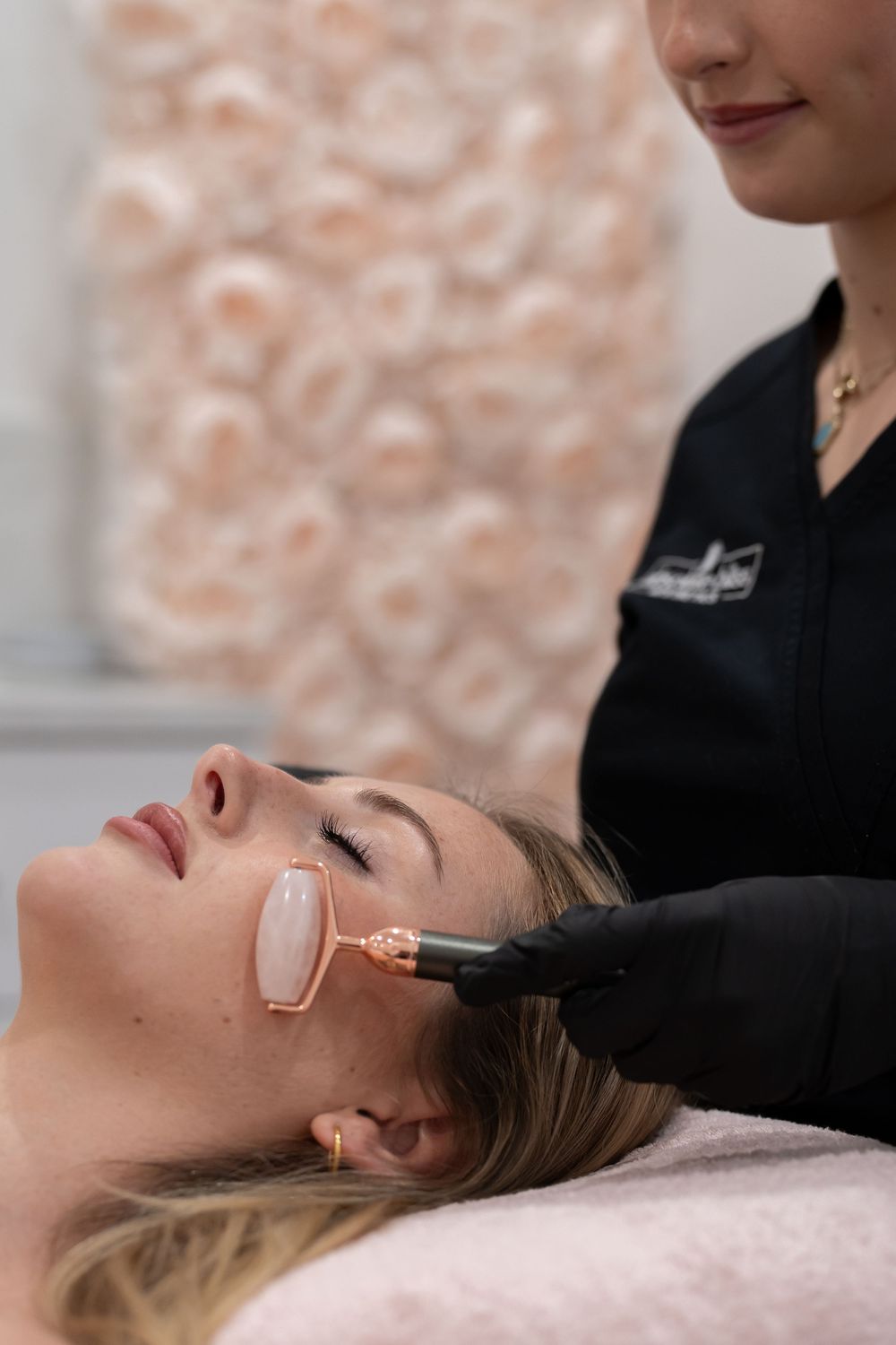 Esthetician performing a facial laser treatment on a woman wearing protective eyewear in a beauty salon.