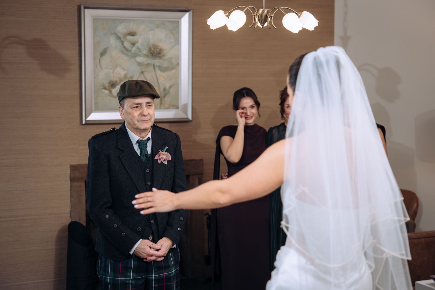Bride laughing joyfully with groom during indoor wedding ceremony, officiant standing nearby.