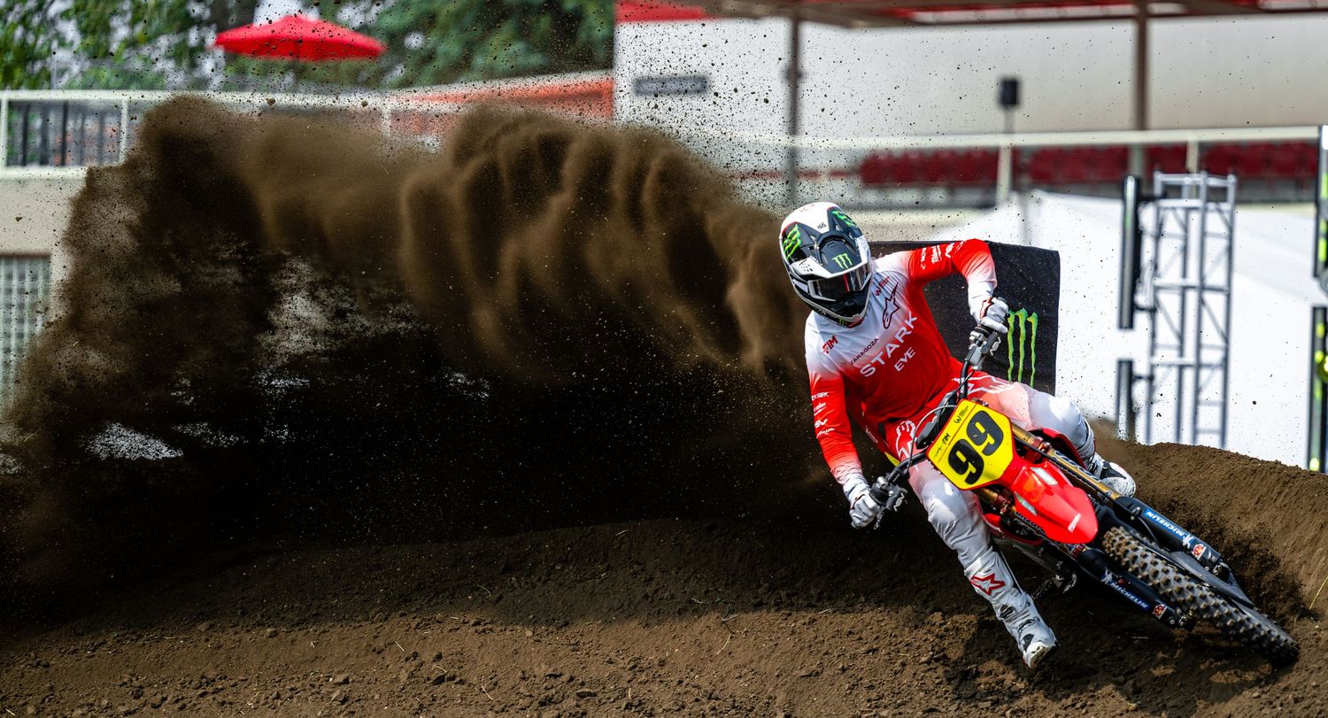Motocross rider performs a jump at the FIM World Supercross Championship Canadian GP with flames blazing in the background.