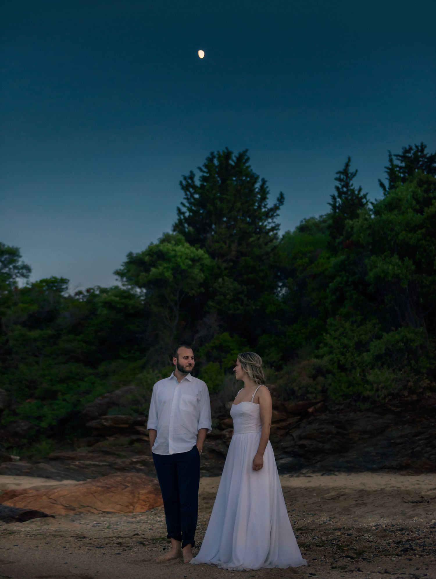 Night sky portrait of a couple standing outdoors with a single bright star above.