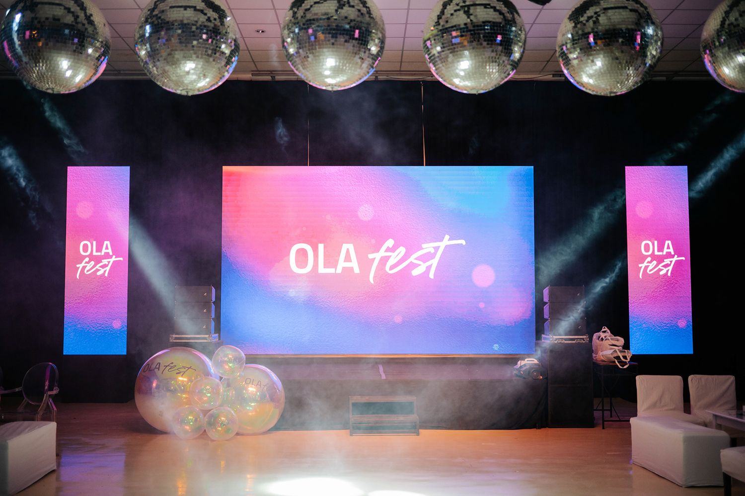 OLA Fest branded stage with large LED screen, disco balls, and colorful balloon decorations.