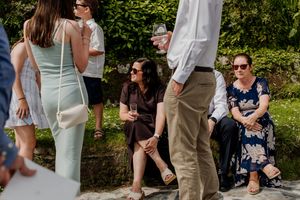 Wedding guests socializing outdoors, with women in summer dresses enjoying drinks at a garden reception.