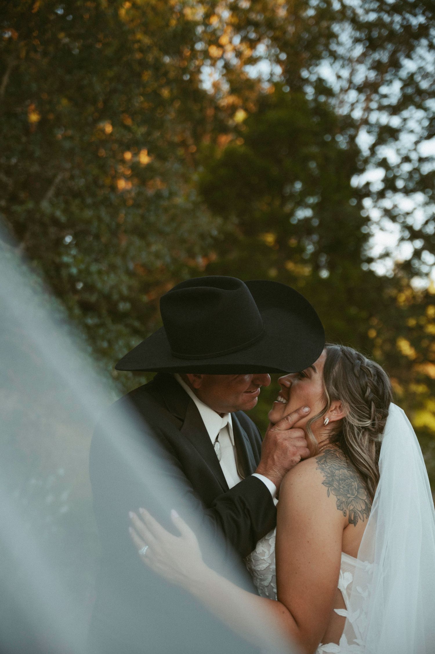 A bride and groom share a romantic kiss in front of snow-capped mountain peaks on their wedding day.