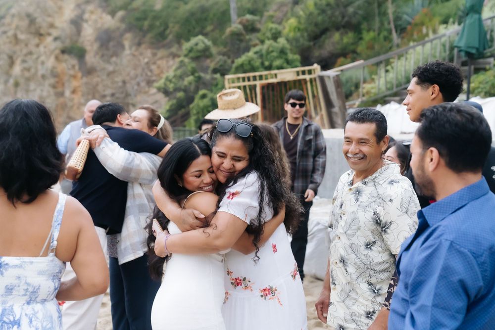 Guests embracing and celebrating at an outdoor beach event with smiles and hugs.