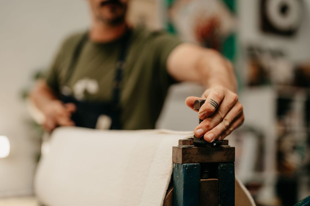 Close-up of a hand adjusting a printing press mechanism in an art studio workshop.