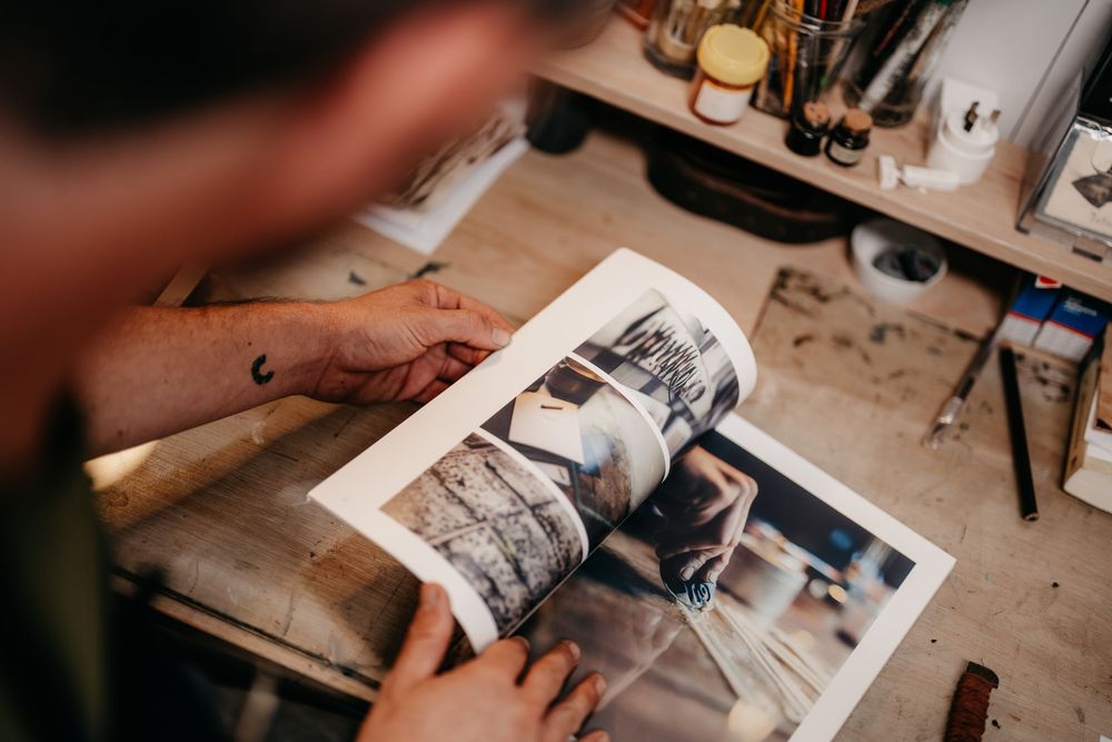 Close-up of hands flipping through a black and white photography book in an art studio.