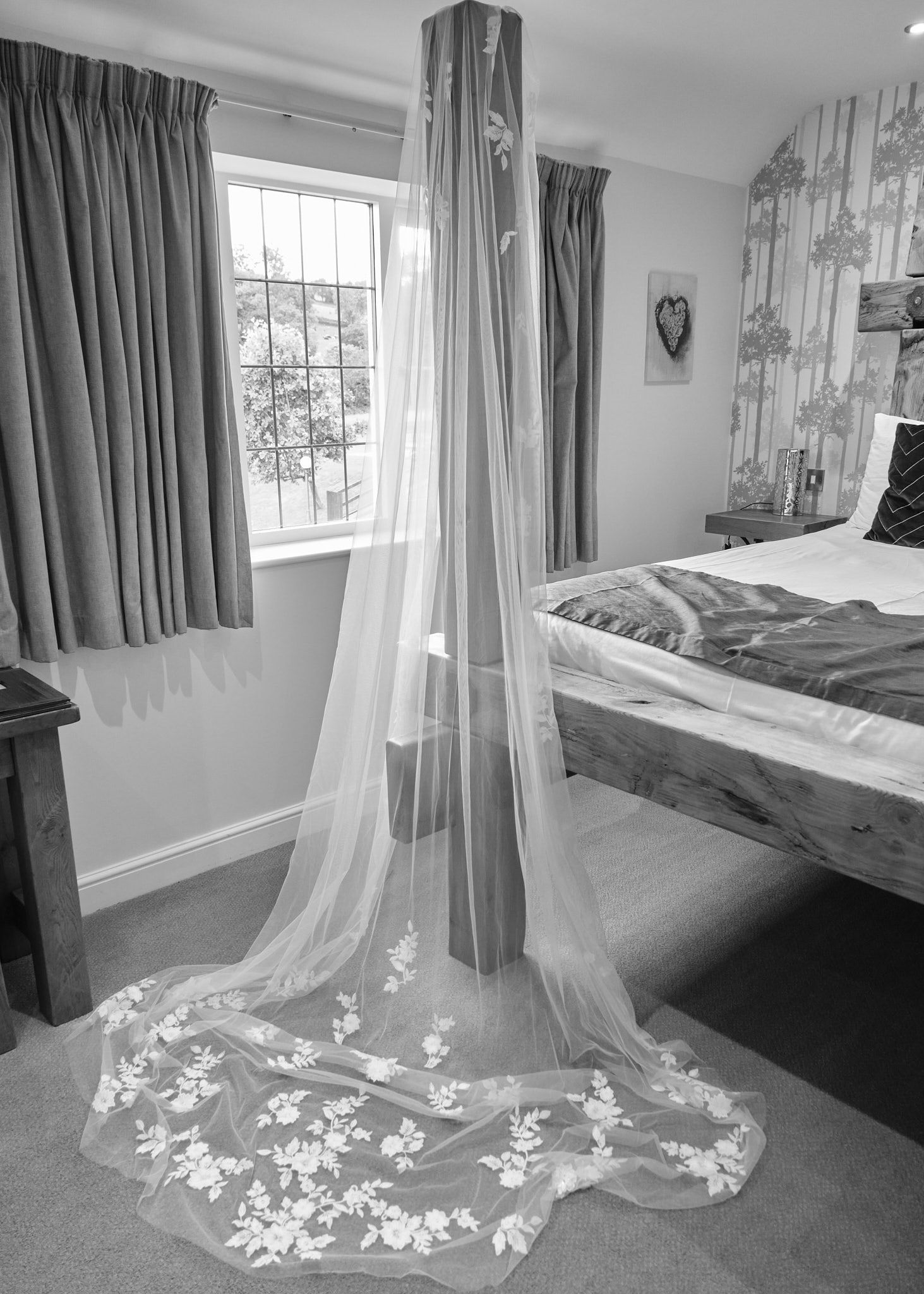 Elegant long lace wedding veil displayed in a bedroom, cascading to the floor with floral embroidery details. White hart inn wedding