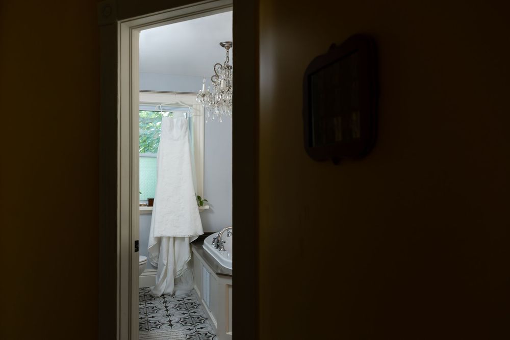 Brides dress handing in the window of a bathroom during the morning of a wedding in london, ontario