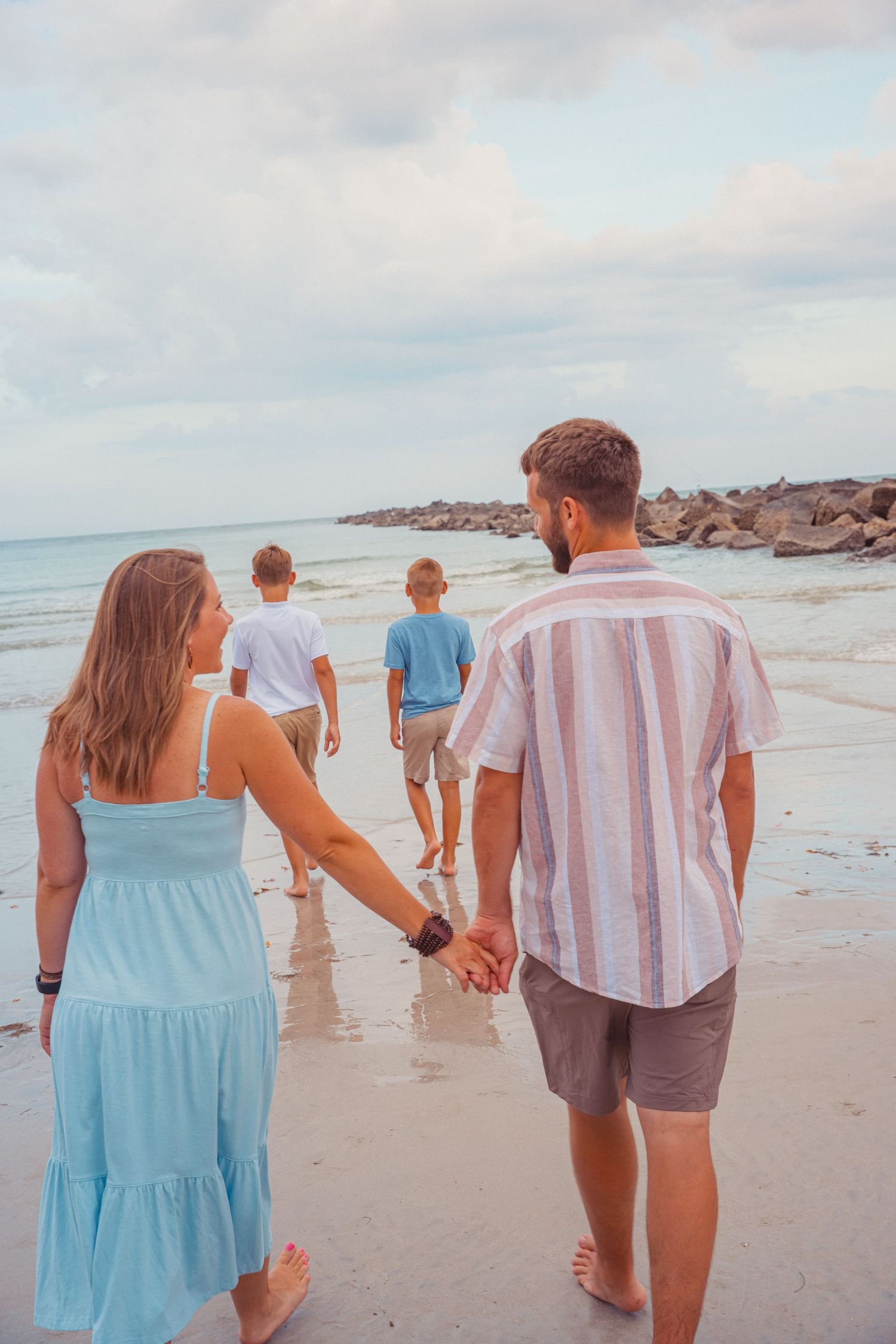 A married couple walks hand in hand behind two brothers on a beach in Florida