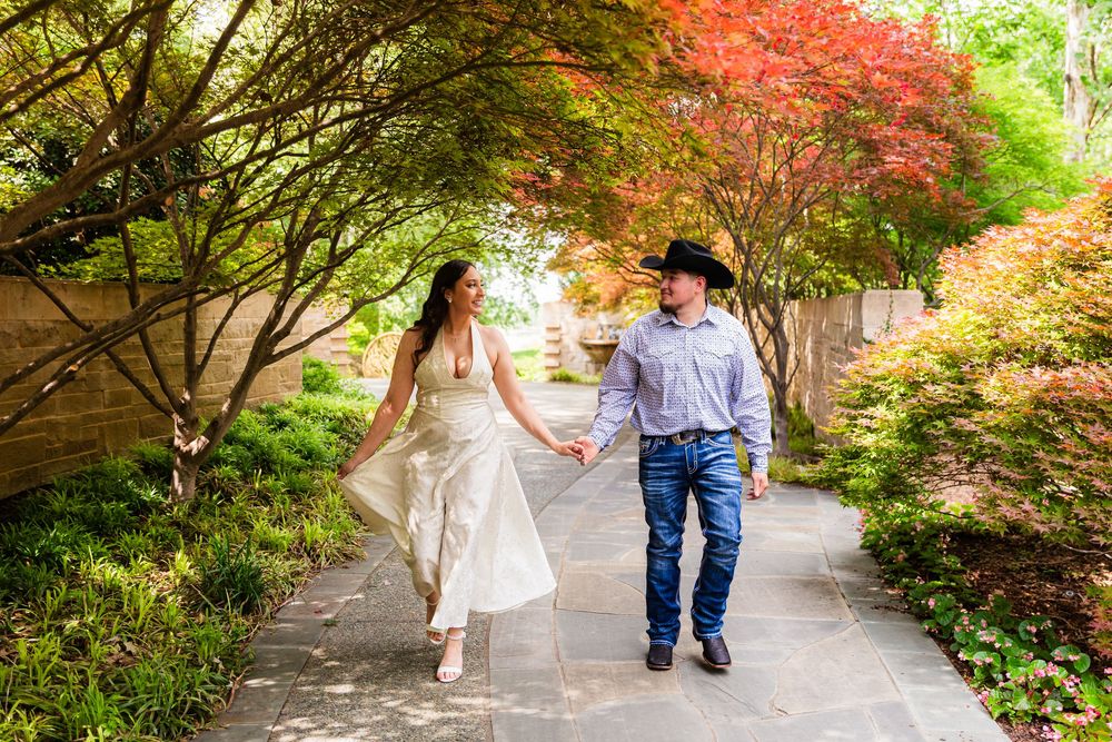Couple holding hands walking through a lush garden path with colorful Japanese maple trees.