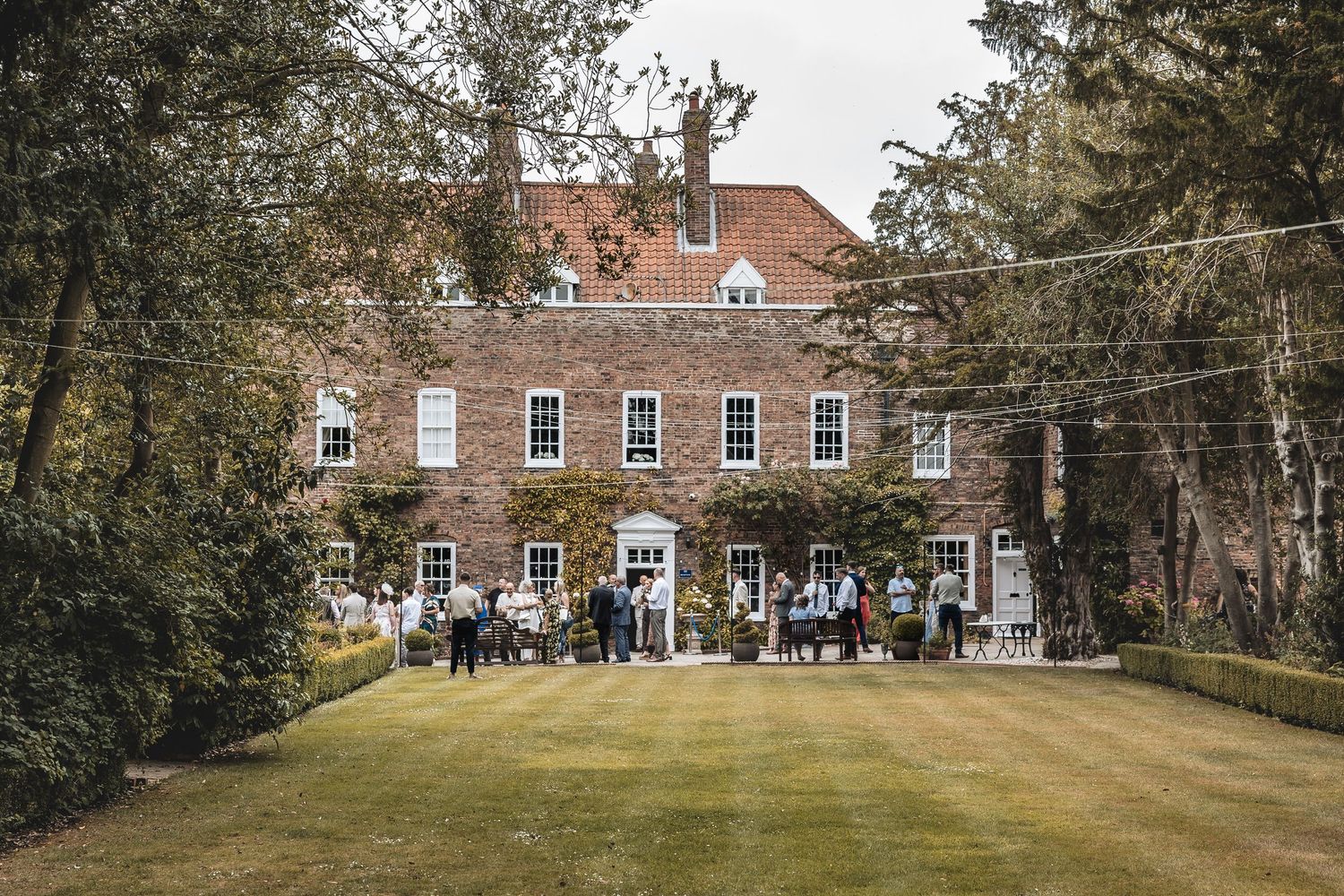 Wedding guests enjoying drinks and chatting outside the venue after the ceremony