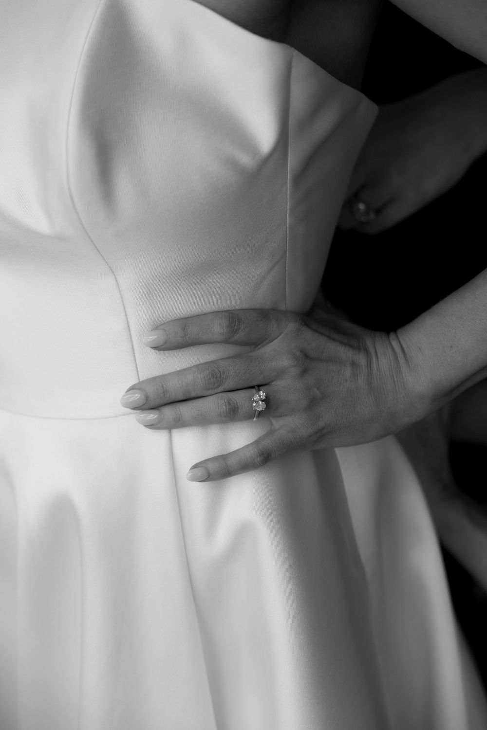 Black and white close-up of bride in strapless gown with diamond engagement ring.