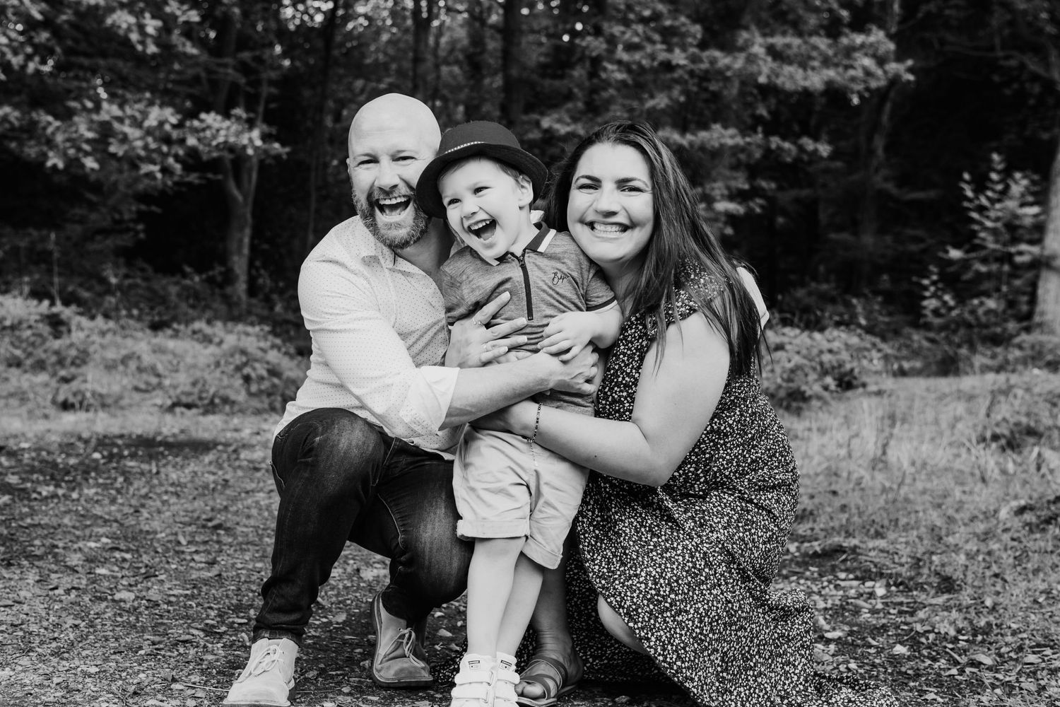 Parents cuddling their young son during a relaxed outdoor family photography session.