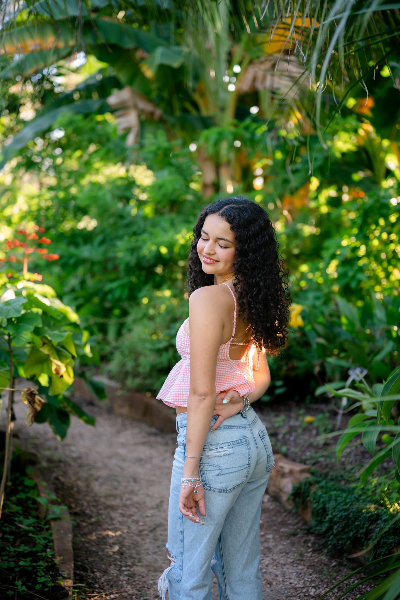 The Woodlands senior girl with curly hair posing among the banana trees.