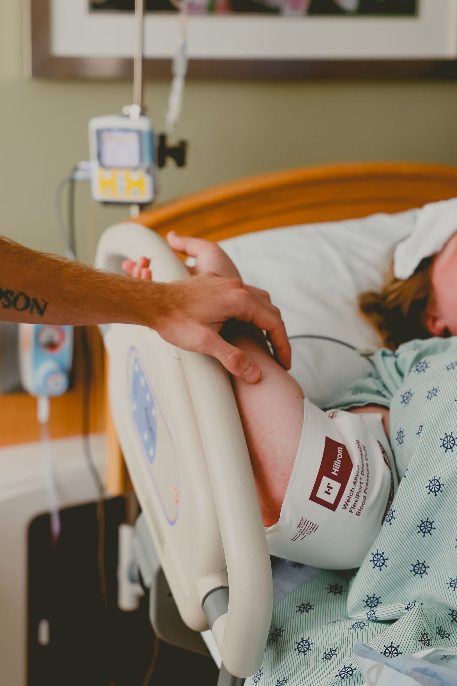A woman in a hospital gown lies in a hospital bed while a partner holds her hand during labor.