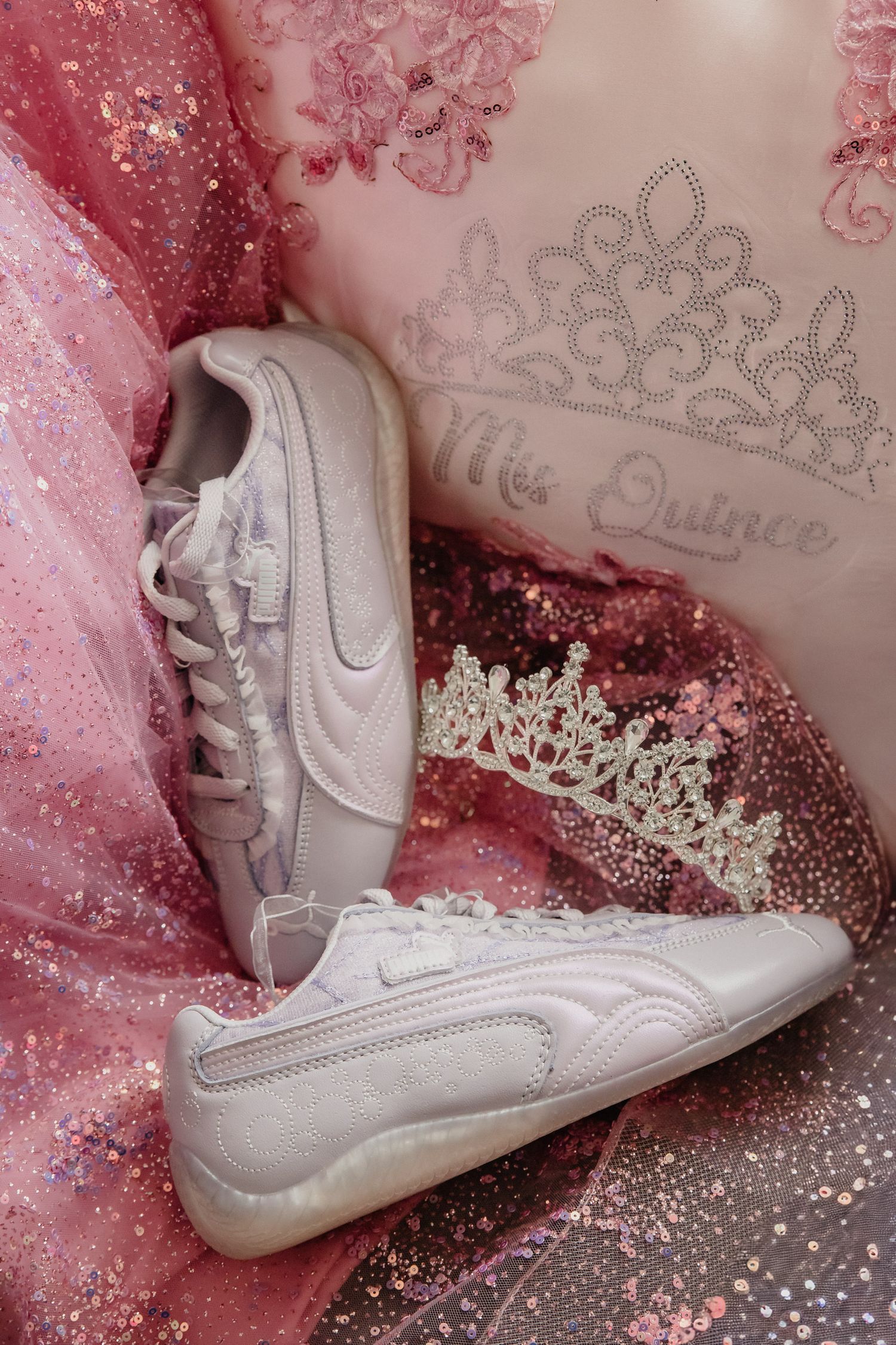 White Puma sneakers with a silver tiara and pink glittery quinceañera decorations for a Miss Quince celebration.