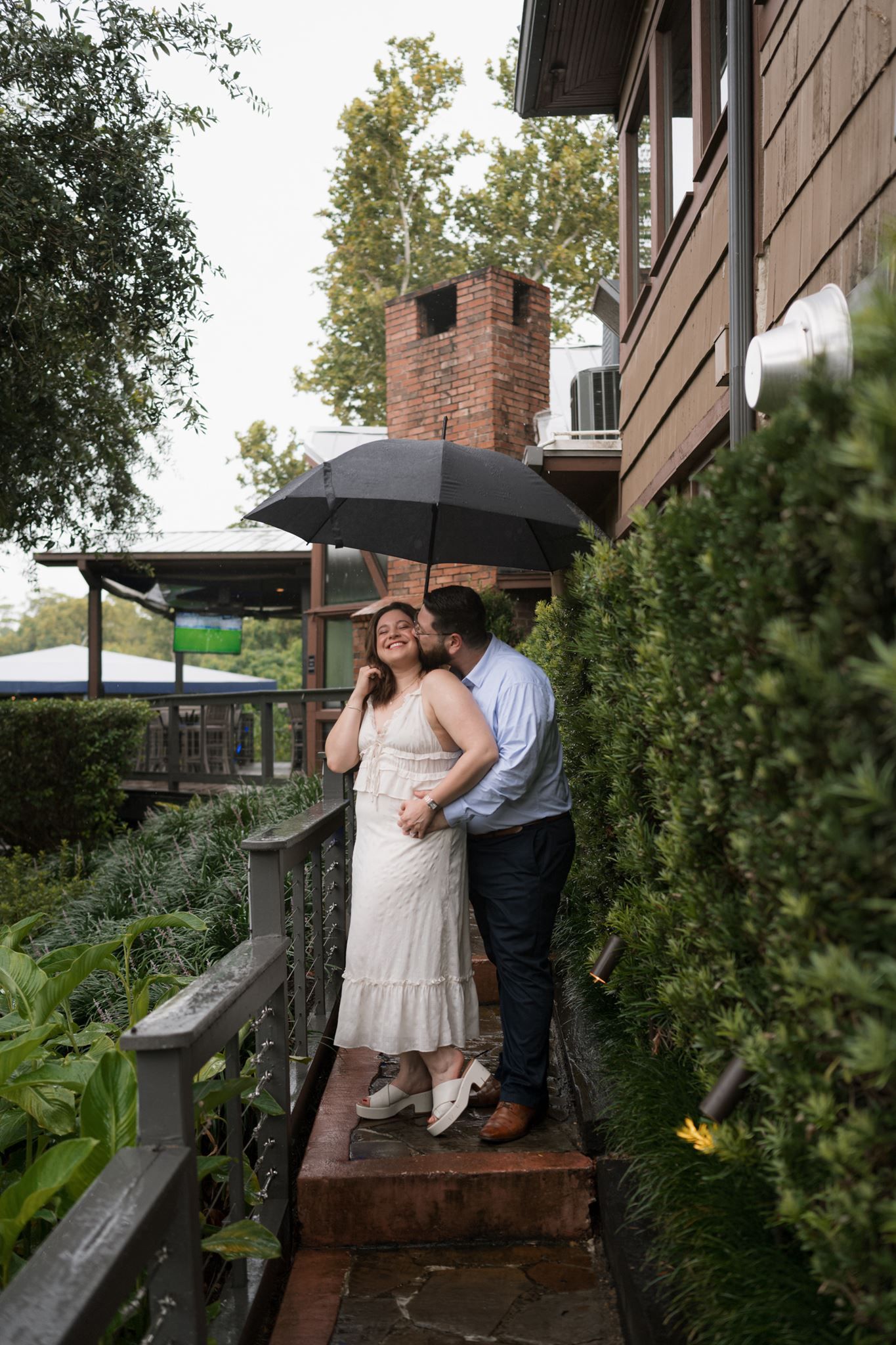 Newly engaged couple kissing beneath the umbrella after their proposal
