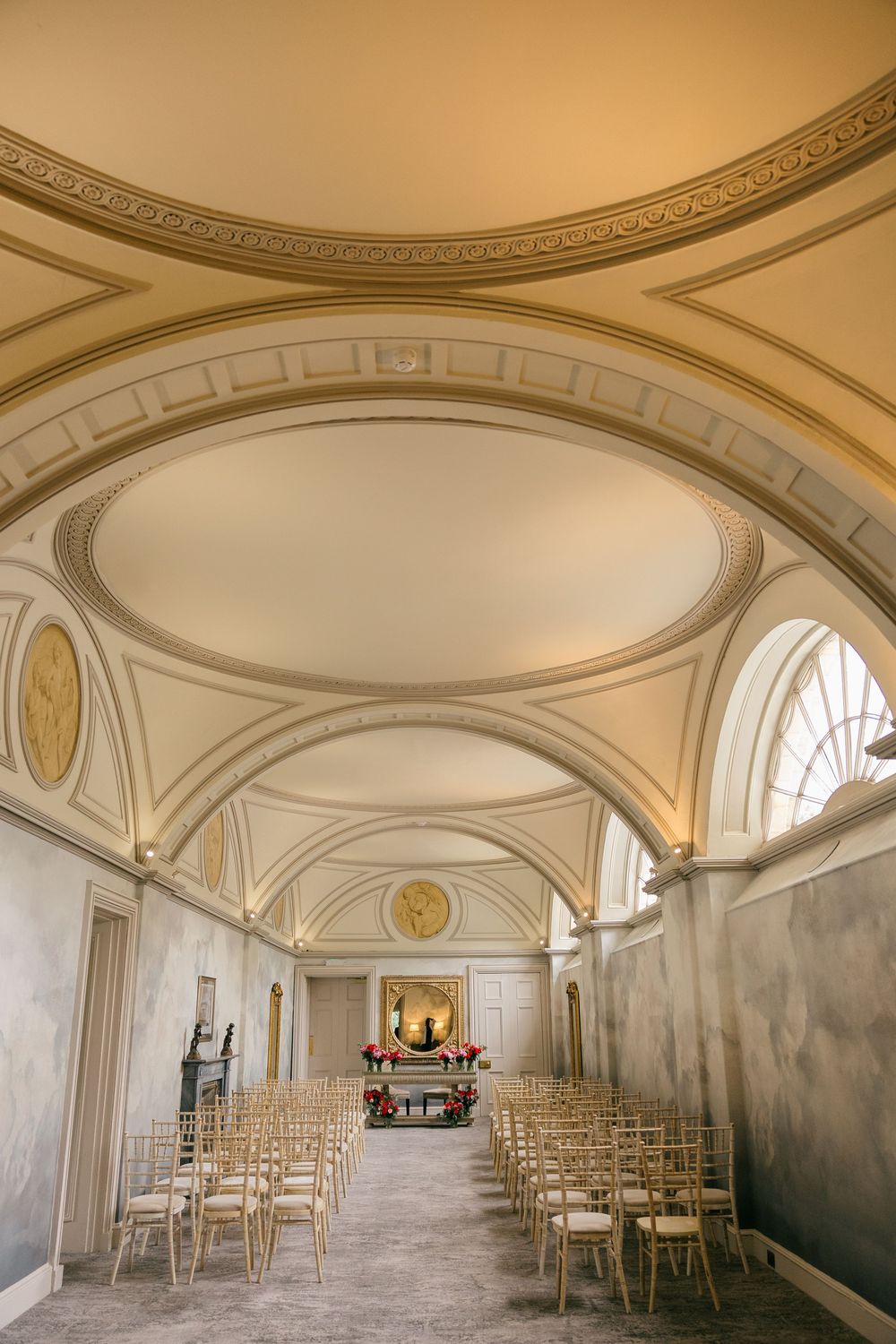 Elegant wedding ceremony hall with vaulted ceilings, gold ornate details, and rows of chairs leading to a floral altar.