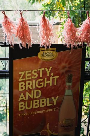 Brown Brothers Pink Grapefruit Spritz sign reading Zesty, Bright and Bubbly, decorated with pink paper tassels.
