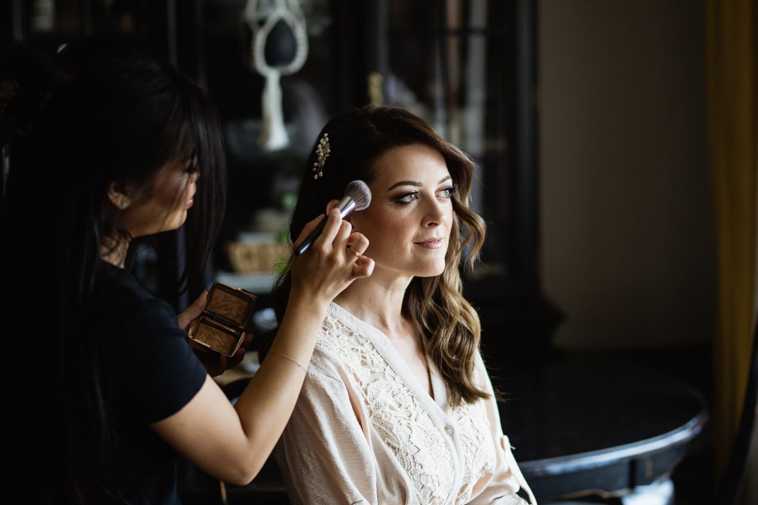 Calgary bride smiling as her makeup artist applies makeup on the wedding morning