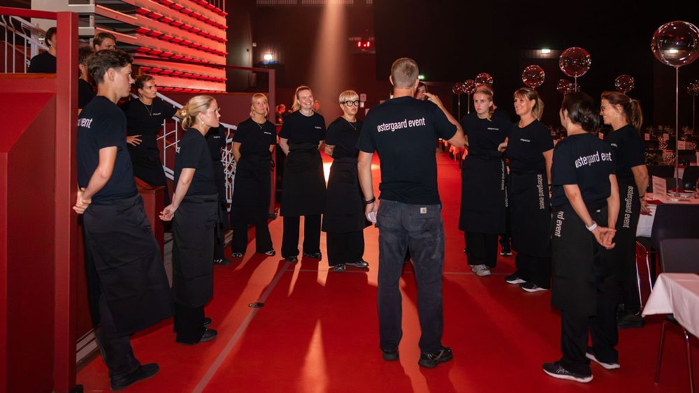 Group of people in black uniforms gathered in a circle at an elegant red-themed event venue.